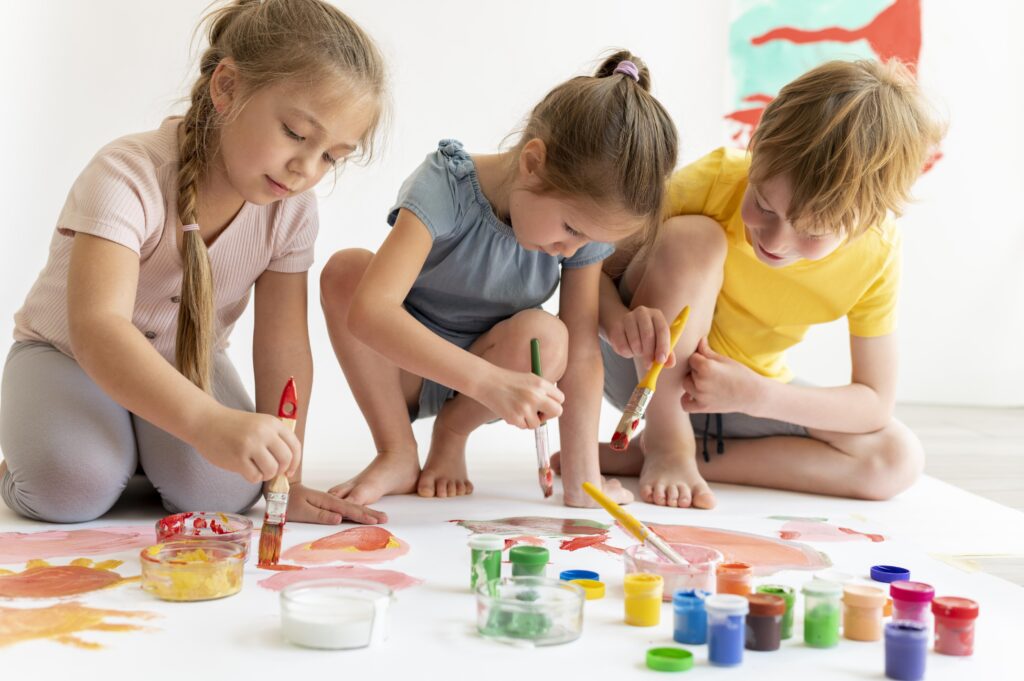 Enfants peignant et mélangeant des couleurs ensemble lors d’une activité créative.
